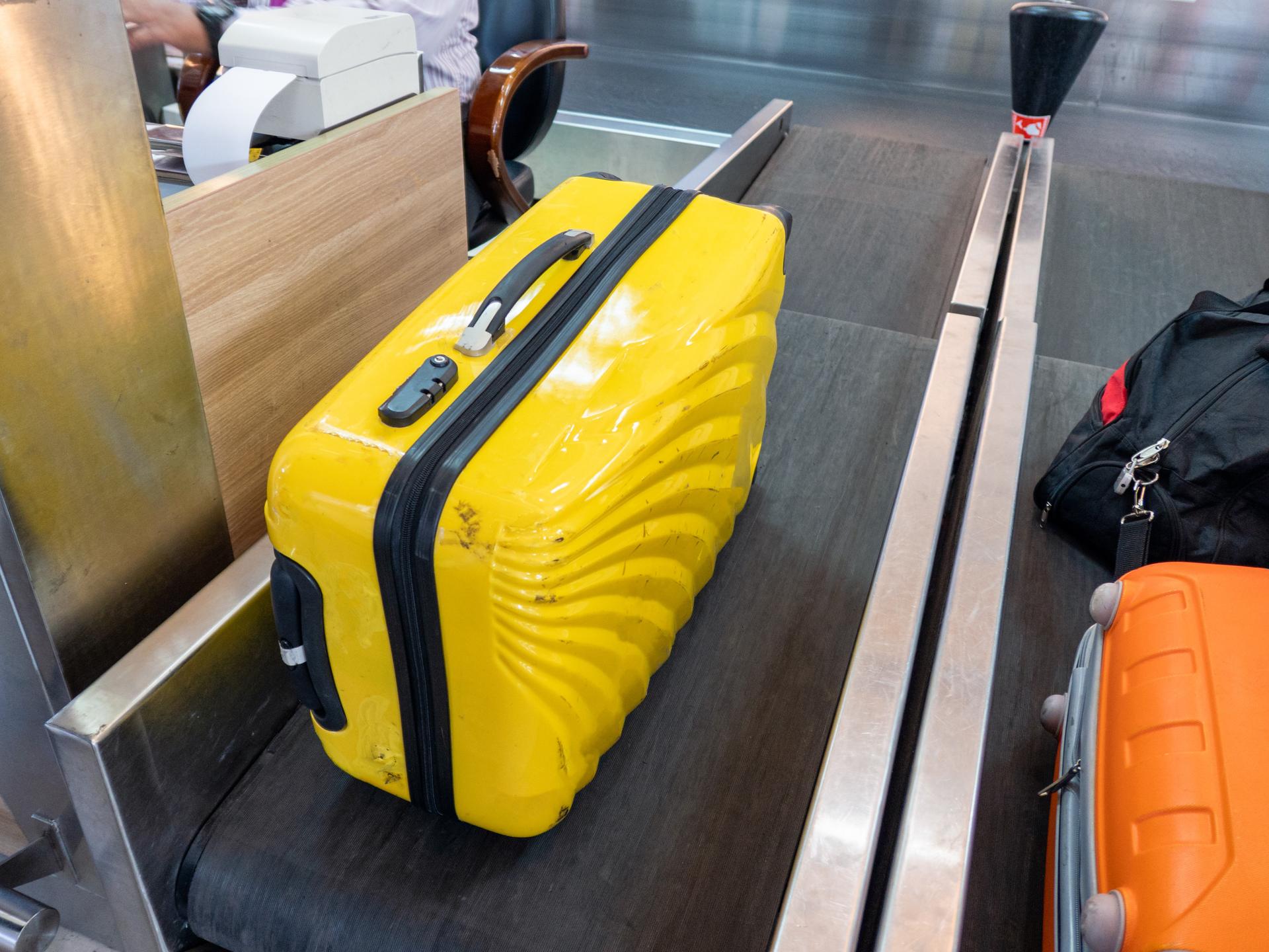 Photograph of passengers checking in baggage at the airport.