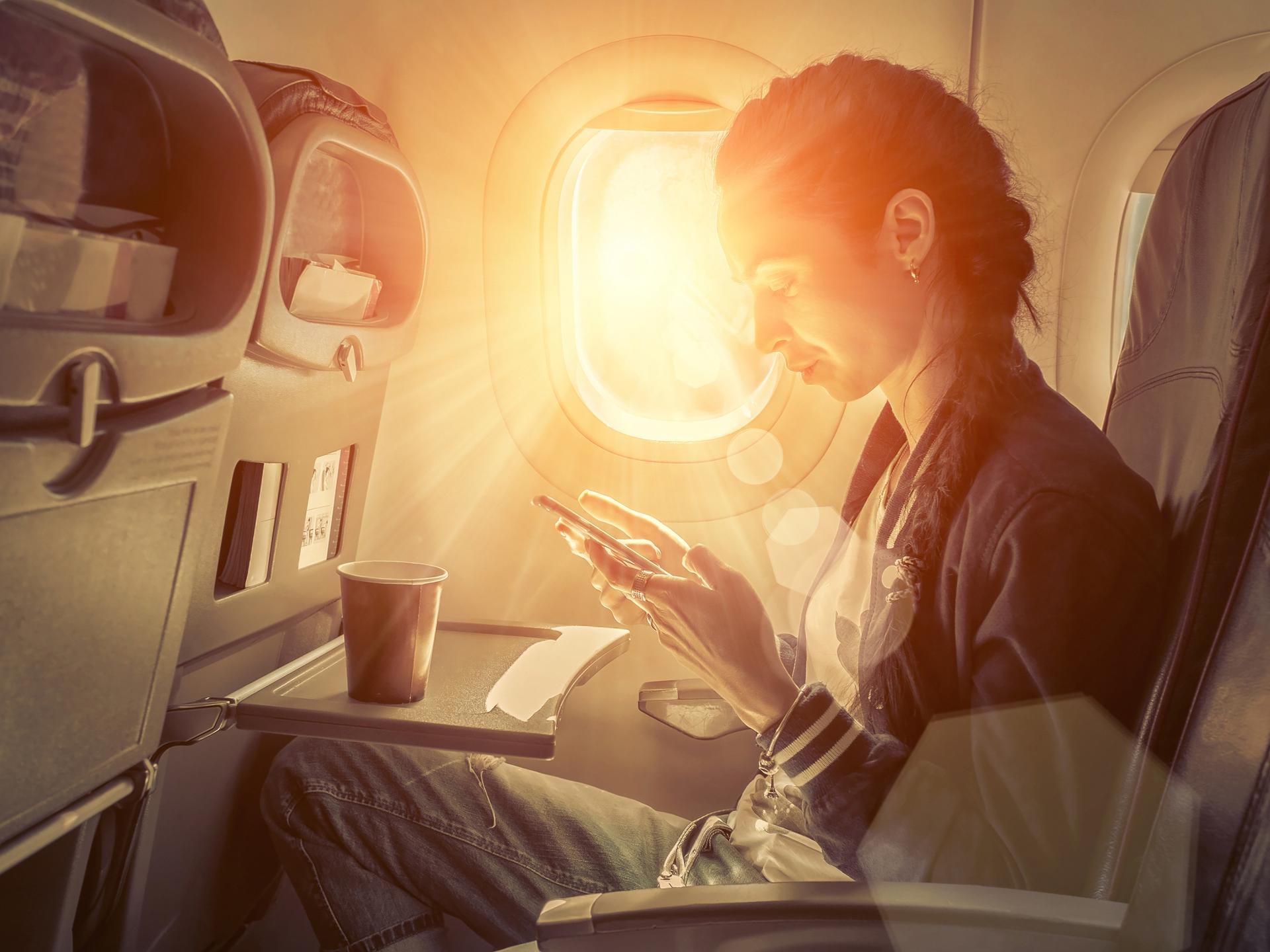 It is a photo that operates an electronic device on an airplane.